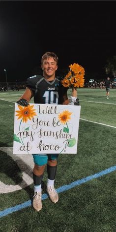 a young man holding a sign that says will you be my sunshine at once?