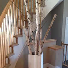 a tall vase filled with branches sitting on top of a wooden floor next to a stair case