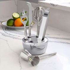 a silver utensil holder with fruit and vegetables in it on a marble countertop