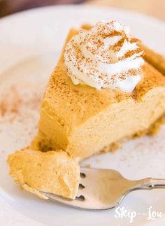 a slice of pumpkin pie on a white plate with a fork and whipped cream topping