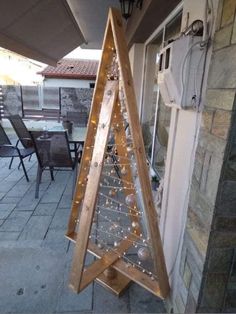 a christmas tree made out of wood and string lights on the side of a building