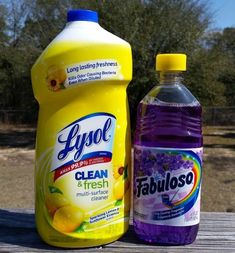 two bottles of laundry detergent and a bottle of fabric cleaner sitting on a picnic table