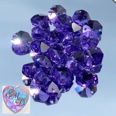 a bunch of purple crystals sitting on top of a blue tablecloth next to a heart