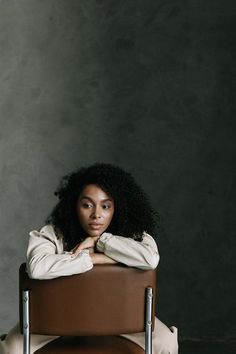 a woman is sitting in a chair with her arms folded over her chest and looking at the camera