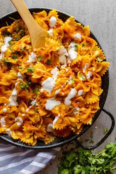 a skillet filled with pasta and cheese on top of a white table next to parsley