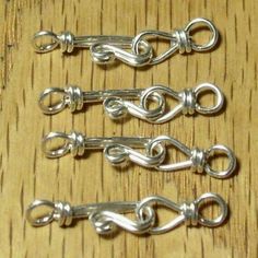 five silver colored metal hooks on a wooden surface