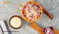 a wooden bowl filled with coleslaw next to a small bowl of mayonnaise