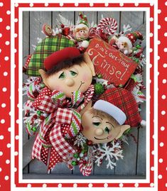 a christmas wreath with two elfs on it