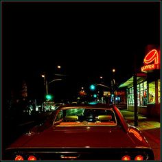 a red car parked in front of a store at night