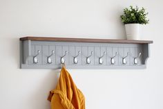 a coat rack with hooks on it next to a potted plant and towel hanger