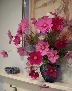 a vase filled with pink flowers sitting on top of a mantle