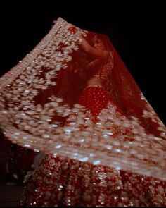 a woman in a red and white dress is dancing with her veil over her head