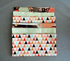 four wallets are stacked on top of each other with different patterns and colors in them