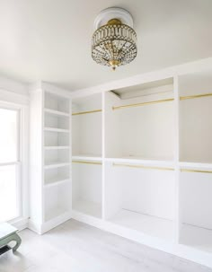 an empty room with white shelving and a chandelier