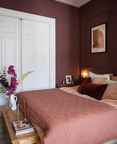 a bed with pink sheets and pillows in a bedroom