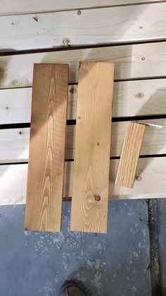 two pieces of wood sitting on top of a wooden floor next to a pair of scissors