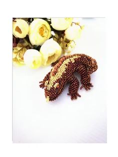 a gecko is sitting next to flowers on a white surface with yellow and red petals