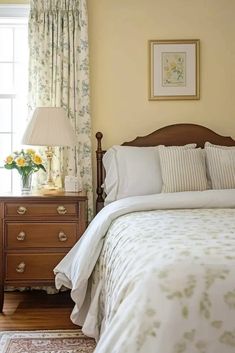 a bed sitting in a bedroom next to a window with curtains on the windowsill