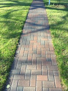 a red fire hydrant sitting on the side of a brick road next to a park