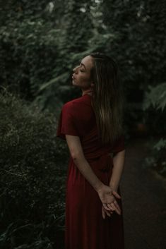 a woman in a red dress is looking up into the sky with her eyes closed