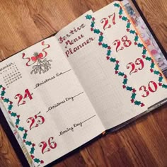 an open planner with christmas decorations and numbers on the pages, sitting on a wooden table