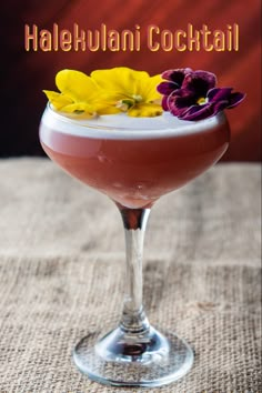 a cocktail in a coupe glass with flowers on the rim and text that reads halekulanii cocktail