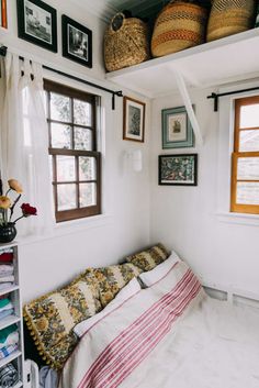 a bed sitting under a window next to two baskets on top of a shelf in a bedroom