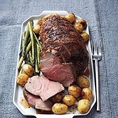 a plate with meat, potatoes and asparagus on it next to a fork