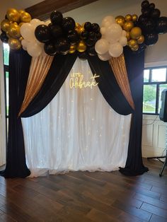 balloons and streamers decorate the backdrop for an elegant celebration with black, gold and white colors