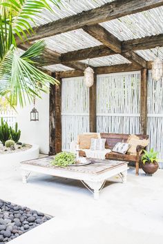 an outdoor living area with couches, tables and potted plants