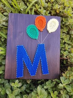 the letter m is made out of bead and beads with two flowers on it