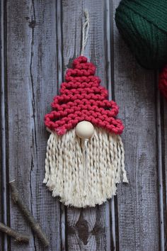 a knitted gnome ornament sitting on top of a wooden table next to yarn balls