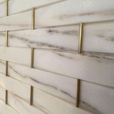 an instagramted photo of white marble tile with gold accents on the backsplash