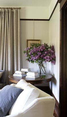 a vase with purple flowers sitting on top of a table next to a white couch