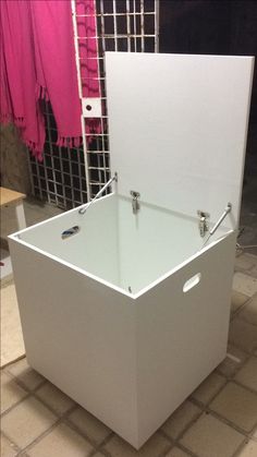 a large white box sitting on top of a tile floor next to a pink towel rack