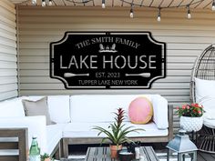 a sign that says the smith family lake house next to a couch and table with potted plants