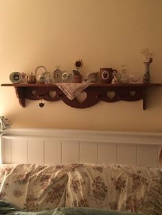 the shelf above the bed is filled with tea cups and vases on top of it