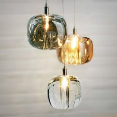 three glass pendant lights hanging from a ceiling