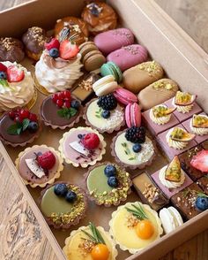 a box filled with lots of different types of cakes and pastries on top of a wooden table