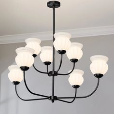 a black chandelier with white shades hanging from it's ceiling in a room