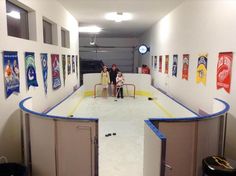 two people are standing in the middle of an ice rink with hockey memorabilia on the walls