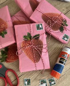 some pink wrapping paper with strawberries on it next to scissors and other crafting supplies