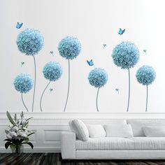 a living room with white furniture and blue flowers on the wall next to a couch