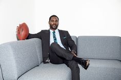 a man in a suit sitting on a couch with an orange ball behind his back