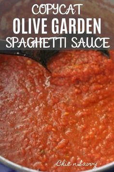 a pot filled with red sauce sitting on top of a blue table cloth next to a black spatula