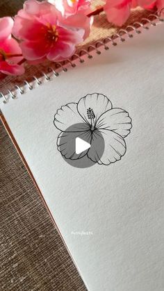 a notebook with an image of a flower on the cover and pink flowers in the background