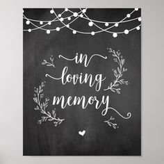 a chalkboard with the words in loving memory written on it and string lights hanging above