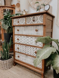 a wooden dresser sitting next to a potted plant