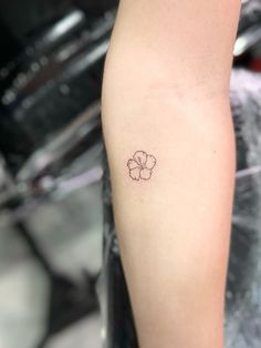 a small four leaf clover tattoo on the left inner arm and lower arm, which is also in black ink