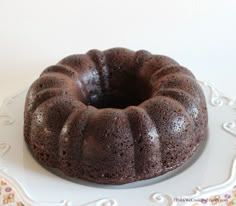 a bundt cake sitting on top of a white plate next to a flowered table cloth